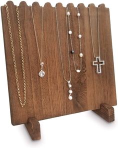 a wooden stand with several different necklaces hanging from it's sides and a cross on the other side