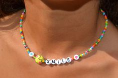 "This dainty necklace is a fun combination of varied, colorful seed beads combined with darling little, emoji smiling faces and the letters spelling smile with hearts.  It is super cute and darling. Lightweight and perfect for a little girl's gift! Clasp is a sterling magnetic clasp (for convenient wear and removal) and findings are all sterling silver. Necklace measures approximately just over 14\" Browse more fun items from my shop here: https://www.etsy.com/shop/uniquebeadingbyme?ref=seller-p Trendy Colorful Beaded Necklaces With Letter Beads, Trendy Colorful Beaded Necklace With Letter Beads, Trendy Birthday Necklace With Letter Beads, Cute Beaded Necklaces With Tiny Beads For Gifts, Cute Beaded Necklaces With Tiny Beads As Gifts, Cute Beaded Necklace With Tiny Beads For Gifts, Cute Everyday Necklaces With Round Beads, Fun Adjustable Necklace For Everyday Wear, Fun Adjustable Necklace For Everyday