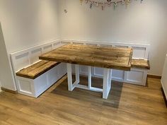 a table and bench in a room with white walls, wood floors and wooden flooring