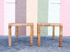 two small wooden tables sitting in front of a multicolored wall with vertical stripes