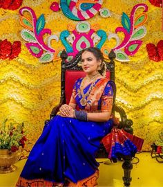 a woman is sitting on a chair in front of a wall with flowers and decorations