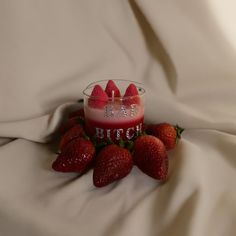 a candle with strawberries sitting on top of it next to some white cloths