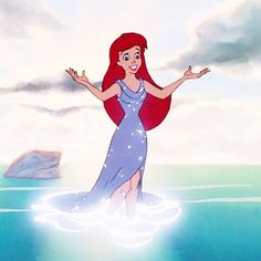 the little mermaid is standing in the water with her arms spread out and she's smiling