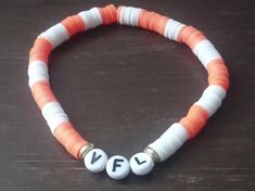 an orange and white beaded bracelet with two letters