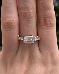 a woman's hand with a ring on it and an emerald stone in the middle