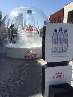 there are two water bottles on display in front of a glass ball that says evian