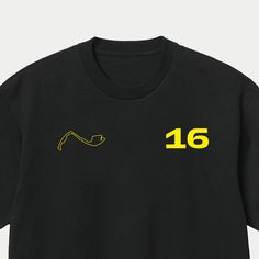 Leclerc 16 Monaco Circuit Formula One Racing T-Shirt Motorsport Clothing F1 Black & Yellow This t-shirt features a sleek and modern design with his driver number prominently displayed along with his home circuit, the Circuit De Monaco. This t-shirt is both comfortable and durable, ensuring that it will last for years to come. Whether you're a die-hard Leclerc fan or simply love the excitement and adrenaline of Formula One racing, this t-shirt is a must-have addition to your wardrobe. It's suitab Black Racing T-shirt With Letter Print, Black Racing Style T-shirt With Letter Print, Black Racing Style T-shirt With Logo Print, Black Racing Tops With Logo Print, Black Crew T-shirt With Team Name, Black Crew Neck T-shirt With Team Name, Racing Style Sports T-shirt With Crew Neck, Black Logo Print T-shirt For Team Events, Black Graphic Print Tops For Motorsport Events