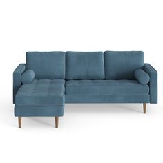 a blue sectional sofa sitting on top of a white floor next to a footstool