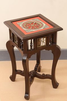 a small wooden table with an intricate design on the top and bottom, sitting on a beige floor