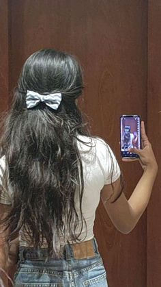 a woman taking a selfie in front of a mirror with her hair pulled back