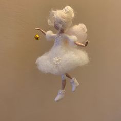 a white ballerina ornament hanging from a string with a gold bead