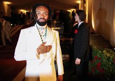 a man in a white suit standing next to another man