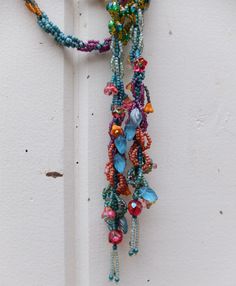 "This hand beaded lariat necklace features a favorite stitch of mine. In the early 1990's this is the first beading stitch I learned. This one is called the spiral rope stitch. The smaller seed beads spiral around a core of large seed beads. This is a newly made, 2019 edition long, seed bead lariat. It measures 54\" long. It can be worn many ways since it is so long. The piece also includes accent beads shaped like flowers, leaves and teardrops. Please let me know if you have any further questio Multicolor Beaded Lariat Necklace With Round Beads, Unique Beaded Lariat Necklace, Festival Lariat Beaded Necklace With Beaded Chain, Turquoise Lariat Beaded Necklace, Festival Beaded Lariat Necklaces, Bohemian Spiral Beaded Necklace, Lariat Beaded Necklaces With Dangling Beads For Festival, Artisan Hand-strung Lariat Beaded Necklaces, Rope Stitch