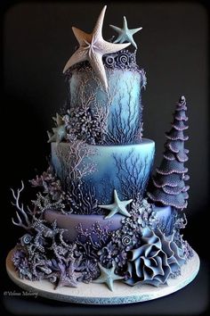 a three tiered cake decorated with blue frosting and starfishs on top