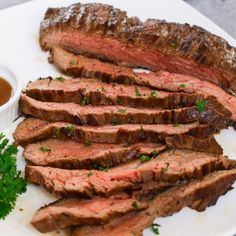 sliced steak on a plate with sauce and parsley