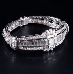 Vintage 1940's .950 Platinum G VVS2 Diamond Cocktail Bracelet 7.58ctw 33.4gMetal Information: .950 PlatinumTotal Weight: 33.4gBracelet Width: 20.6mmBracelet Length: 6"Circa: 1940'sStone InformationMain StoneGem Type: DiamondShape: Emerald (6.5mm x 5.25mm)Color: GClarity/Quality: VVS2Carat Weight: 1.0ctNumber of Stones: 1Accent StonesGem Type: DiamondShape: Baguette (4.5mm x 2.5mm)Color: GClarity/Quality: VVS2Carat Weight: .20ctNumber of Stones: 2Accent StonesGem Type: DiamondShape: Baguette (4.5 Vintage Brilliant Cut Tennis Bracelet For Wedding, Vintage Platinum Tennis Bracelet For Anniversary, Vintage Tennis Bracelet With Single Cut Diamonds, Cocktail Bracelet, Jewelry Website, Custom Jewelry Design, Beautiful One, Estate Jewelry, Diamond Shapes