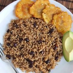 a white plate topped with rice and beans next to an avocado