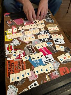 a man is sitting at a table playing with dominos and other pieces of paper