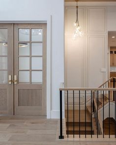 an empty room with wooden floors and glass doors on the front door, next to a stair case