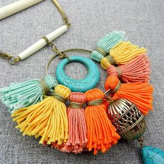 a necklace with tassels and bells hanging from it's side on a gray surface