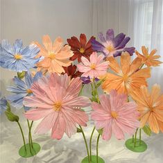 there are many different colored flowers in the vases on the table, and one is painted with acrylic paint