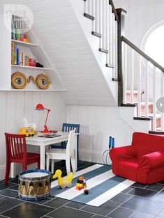 a living room filled with furniture and a stair case next to a white table on top of a hard wood floor