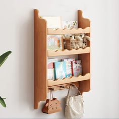 a wooden shelf with books and purses hanging on the wall next to a potted plant