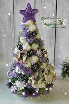 a purple and white christmas tree with flowers on it's top, surrounded by snowflakes