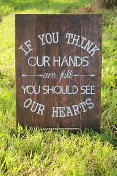 a wooden sign that says, he you think our hands are full you should see our hearts