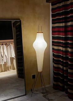 a lamp that is sitting on a stand next to a window with clothes hanging in it