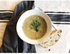 a white bowl filled with soup next to a slice of bread on top of a table