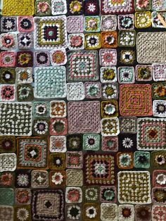 a crocheted blanket with many squares and flowers on the bottom, in various colors