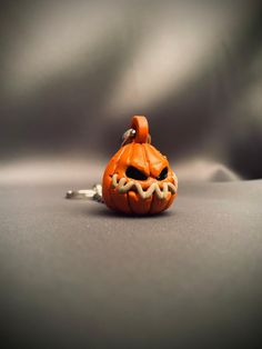 an orange pumpkin shaped keychain on a gray surface