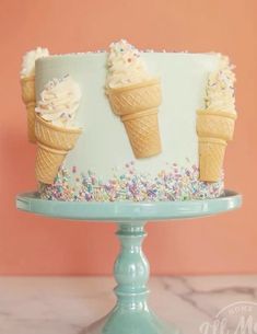 an ice cream cake decorated with sprinkles and two cones on a pedestal