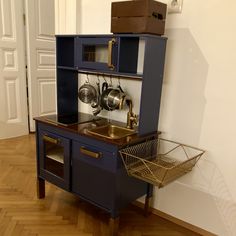 an old fashioned blue kitchen playset with pots and pans on the top shelf