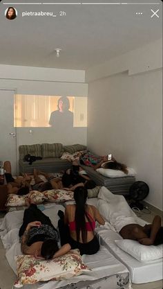 a group of people laying on top of mattresses in a living room next to a tv