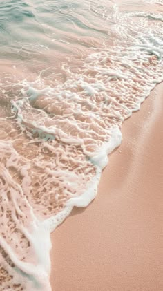 an ocean wave is coming in to the shore and it's white foam on the sand