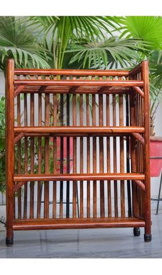 a wooden rack with four shelves in front of some potted plants