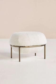 a white ottoman sitting on top of a wooden table next to a beige wall and floor