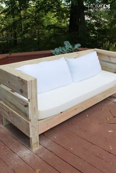 a couch made out of pallet wood sitting on top of a wooden deck next to trees