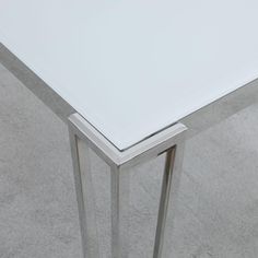 a white table sitting on top of a carpeted floor next to a metal frame