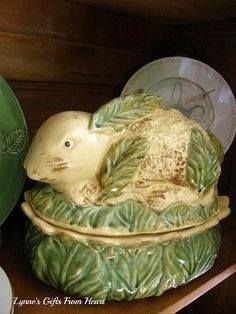 a ceramic animal sitting on top of a wooden shelf next to plates and bowls,