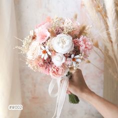 a bridal bouquet being held by someone's hand