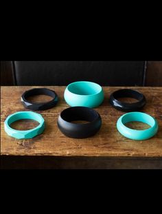 five pieces of black and teal colored plastic sitting on top of a wooden table