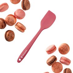 macaroons and a spatula on a white surface with pink icing next to them