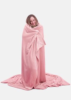 a woman wrapped in a pink blanket on top of a white floor and smiling at the camera