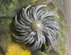 "This beautiful statement brooch features alternating smooth and textured silver pinwheel spokes arranged around a faux pearl. Part of Sarah Coventry's 1969 collection. Dimensions: 7cm diameter. Signed with the \"Sarahcov\" hallmark on the reverse. PLEASE READ: In good vintage condition with small scuffs on the central pearl and some wear to the ends of a few spikes (the price reflects the less than perfect condition) The rollover clasp is in good working order. Please note that all jewellery sold at Cheryl's Treasure Box is in vintage condition and I encourage you to look at the detailed photos. All stones / metals are costume unless otherwise stated. IMPORTANT I am unable to ship to Germany due to their packaging laws. I will have to cancel any orders placed from there." Statement Brooch, Sarah Coventry, Treasure Box, Coventry, Selling Jewelry, Vintage Jewellery, Antique Jewelry, Faux Pearl, Hallmark