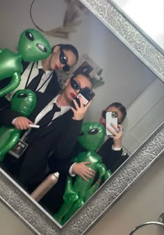 two people in suits are taking a selfie with their cell phones and one is holding a frog