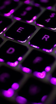 a close up view of a keyboard with purple lights on it's backlit keys