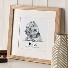 a drawing of a dog in a wooden frame on a shelf next to a vase